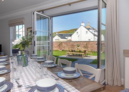 A photograph from one of the showhouses at the Chapelton development, showing the open plan dining area and open patio doors leading out to the expansive garden area.