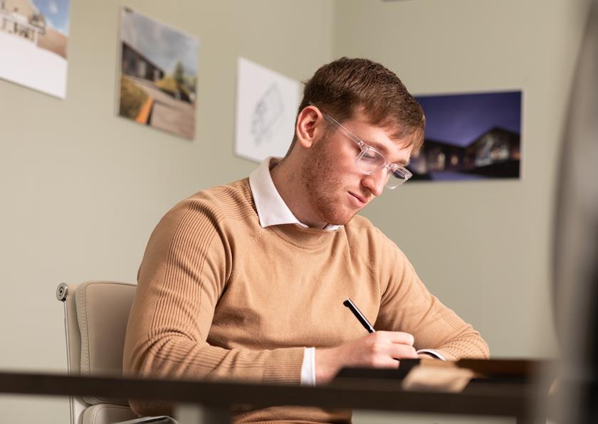 Staff member making notes during a client meeting in Denham Youd offices.