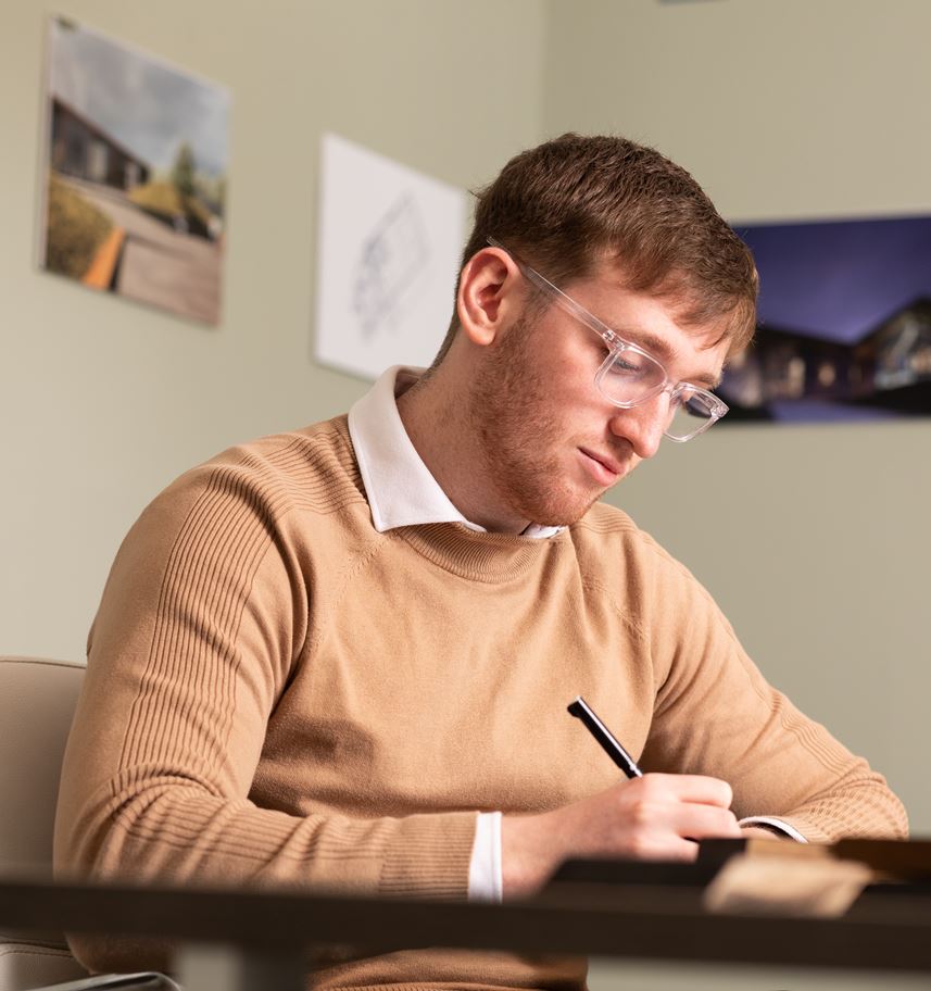 Staff member making notes during a client meeting in Denham Youd offices.