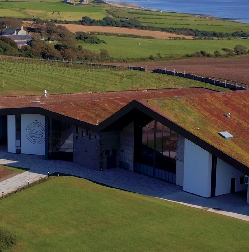 Drone photograph showing Lagg Distillery from above, featuring the surrounding landscape and the sea beyond.