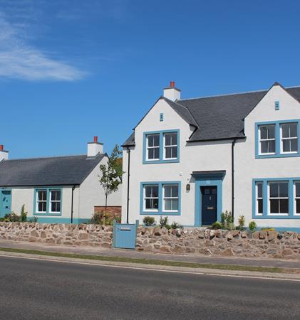 A bright photograph of a blue and white house at the Chapelton development.
