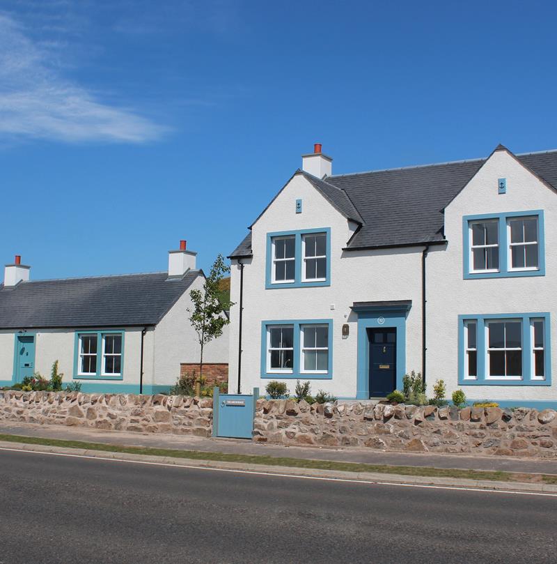 A bright photograph of a blue and white house at the Chapelton development.