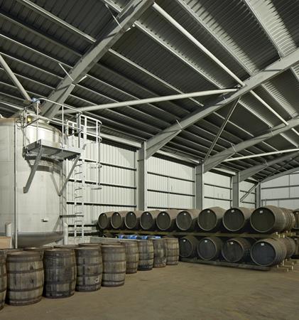 Photograph showing inside the bonded warehouses, featuring multiple whisky barrels.